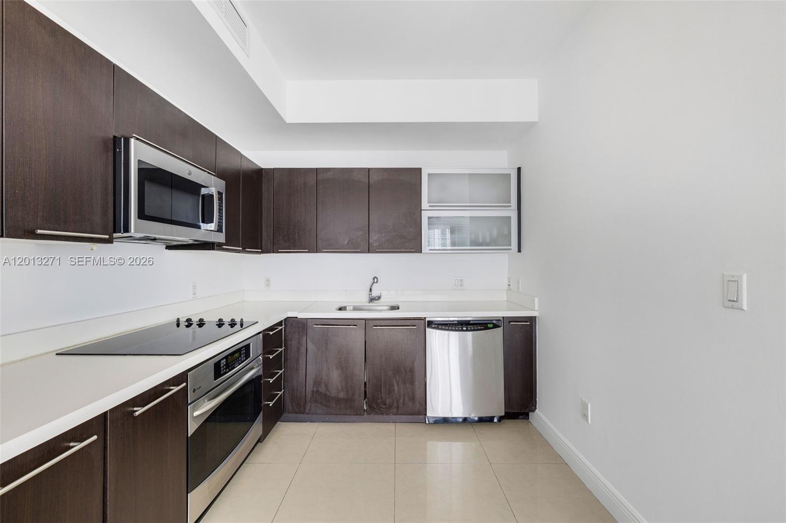 A kitchen features dark wood cabinets, stainless steel appliances, white countertops, and light tile flooring — 90 SW 3rd St # 2504, Miami FL 33130, MIAMI, FL