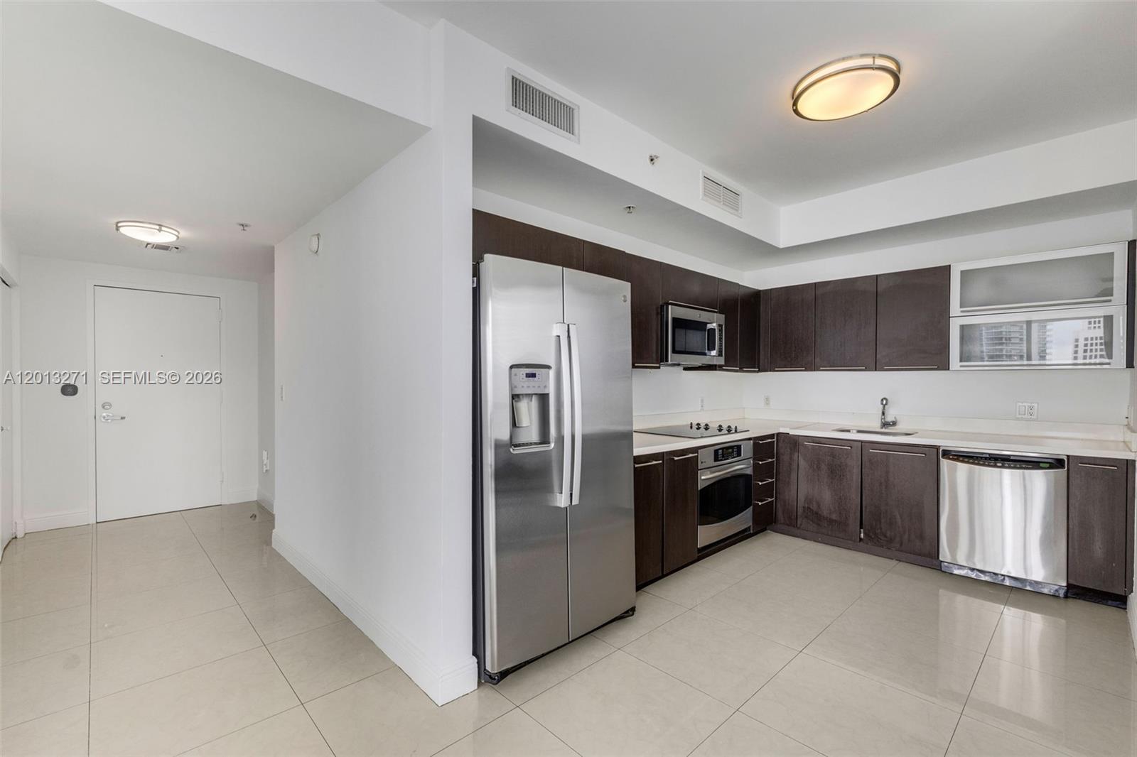 A kitchen features dark wood cabinets, stainless steel appliances, and light tile flooring — 90 SW 3rd St # 2504, Miami FL 33130, MIAMI, FL