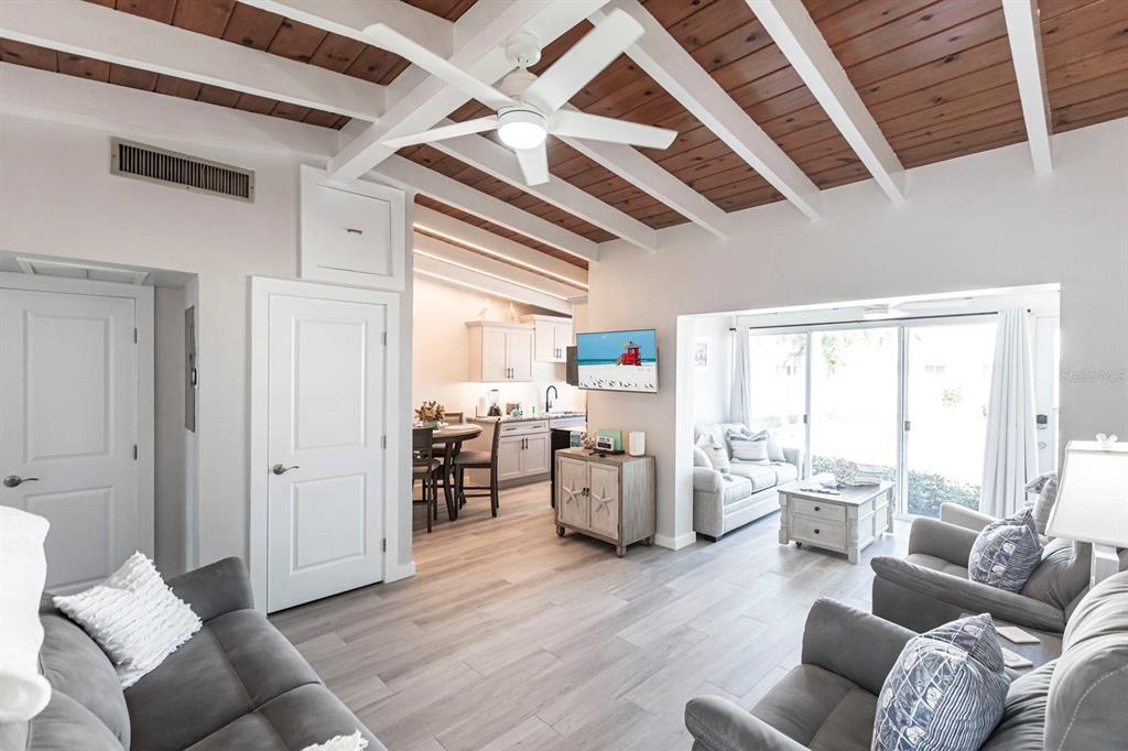 An open-concept living room and kitchen feature white exposed beams and wood-paneled ceilings — 6006 MIDNIGHT PASS ROAD UNIT 65, SARASOTA, FL
