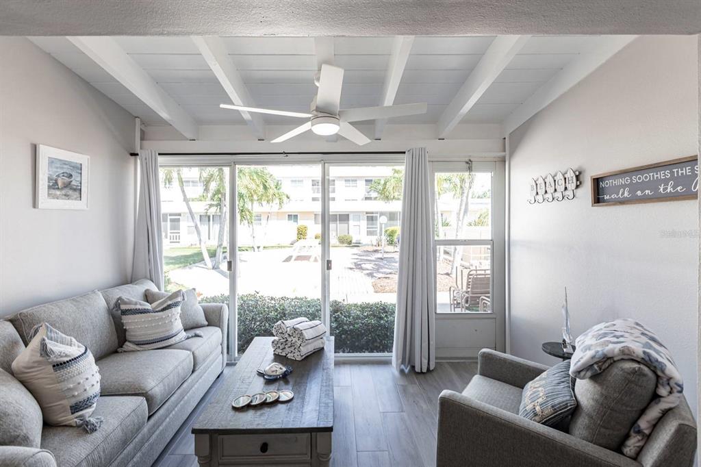 A living room features a gray sofa, an armchair, a coffee table, and sliding glass doors — 6006 MIDNIGHT PASS ROAD UNIT 65, SARASOTA, FL