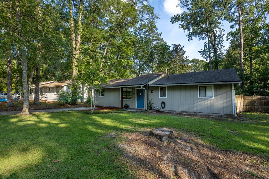 A single-story house with gray siding and a blue front door sits on a grassy lot — 2937 NW 41ST PLACE, GAINESVILLE, FL