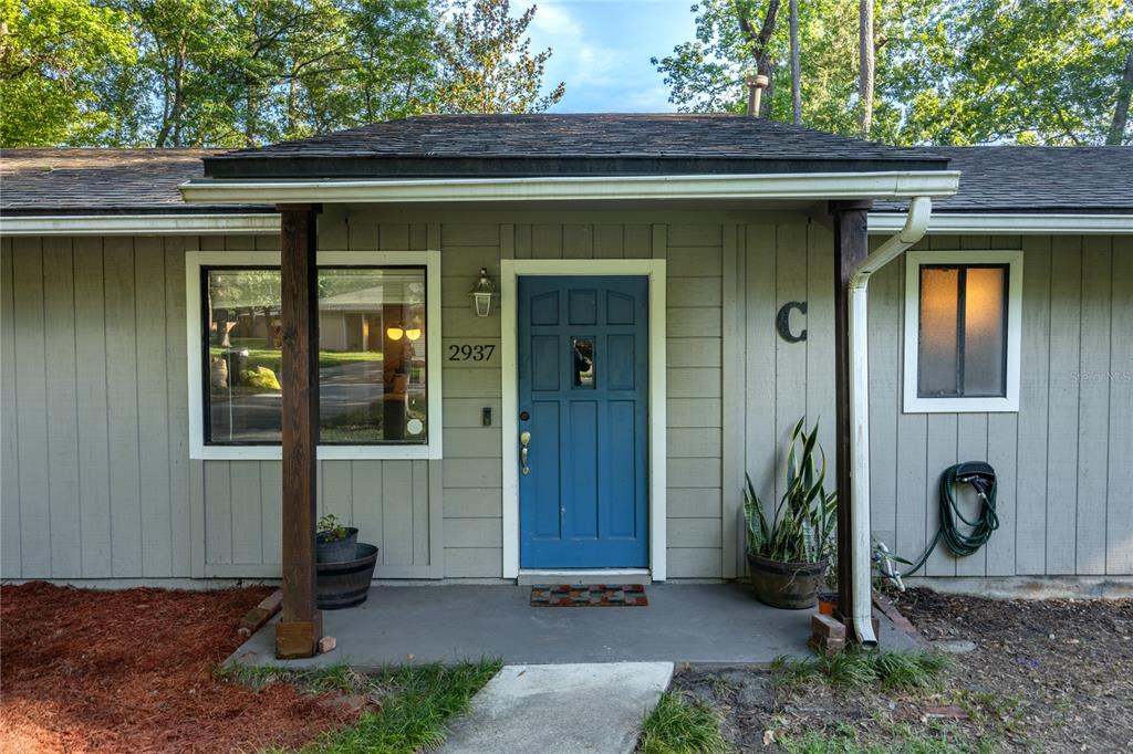The exterior of a single-story home features a blue front door and a covered porch — 2937 NW 41ST PLACE, GAINESVILLE, FL