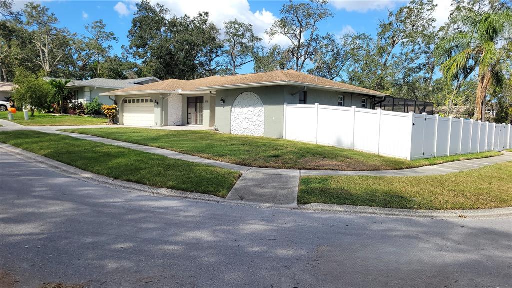 A single-story house with a white fence, a garage, and a textured arched wall feature — 215 MEADOWCROSS DRIVE, SAFETY HARBOR, FL