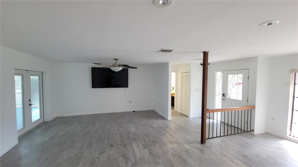 A living room with light wood-look flooring, a ceiling fan, and a wooden room divider — 215 MEADOWCROSS DRIVE, SAFETY HARBOR, FL