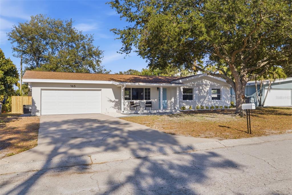 A single-story house with a white exterior, a two-car garage, and a front porch — 165 PINEWOOD AVENUE, CLEARWATER, FL