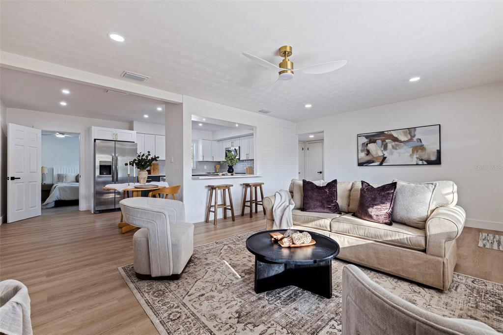 A living room with a beige sofa, round coffee table, and an open kitchen view — 165 PINEWOOD AVENUE, CLEARWATER, FL