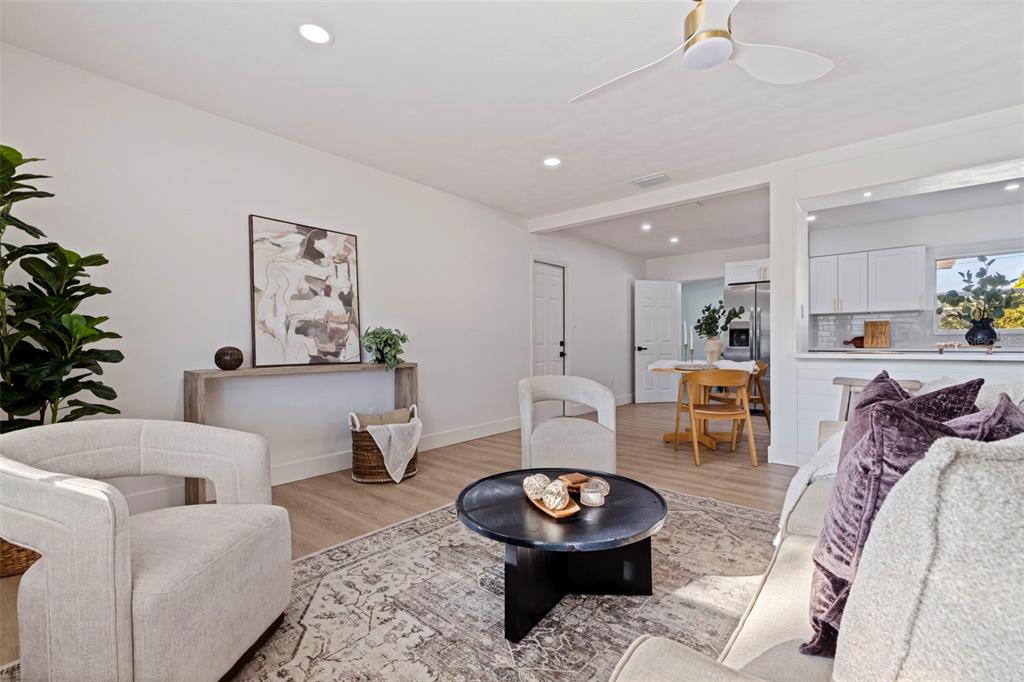 A bright living room features light wood flooring, a round coffee table, and neutral furniture — 165 PINEWOOD AVENUE, CLEARWATER, FL
