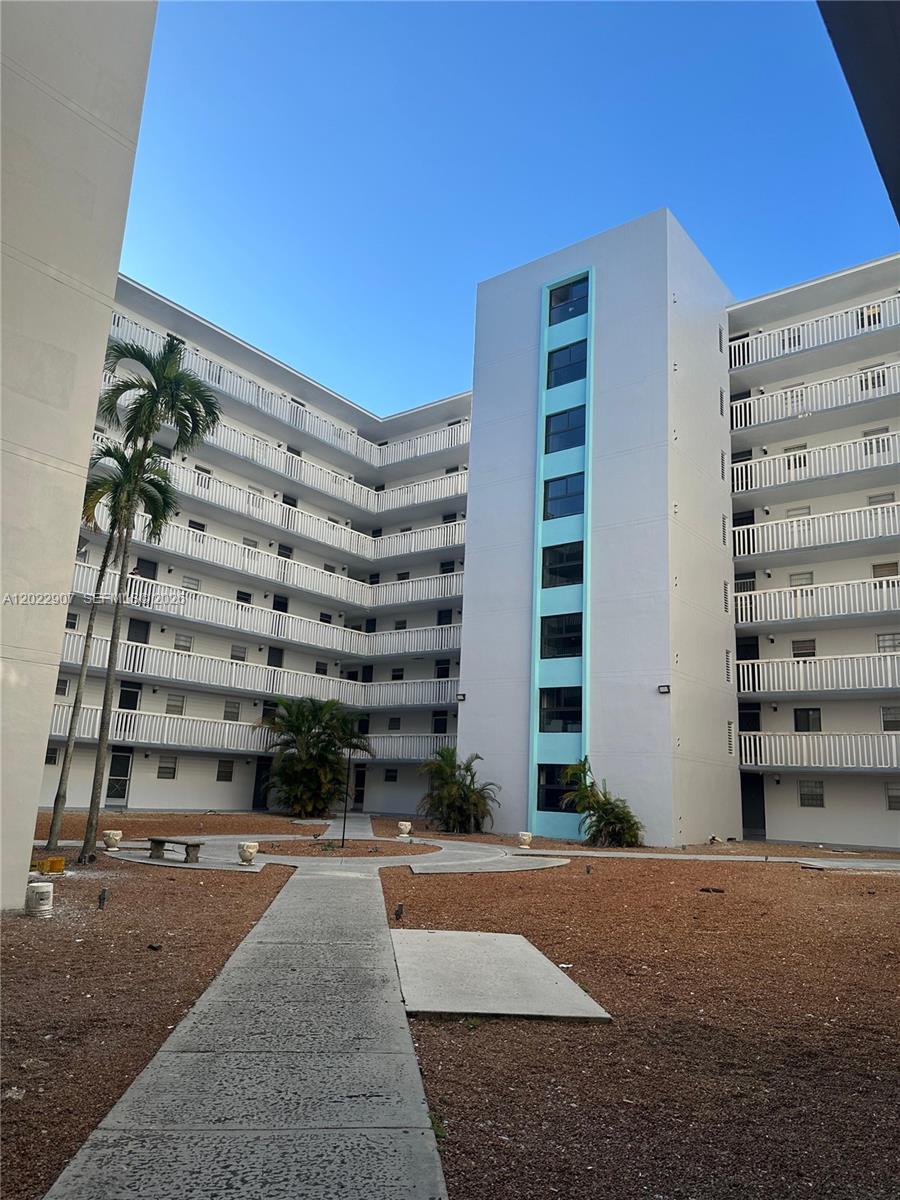 An exterior view of a multi-story apartment building with balconies surrounding a central courtyard — 15600 NW 7th Ave # 507, Miami FL 33169, MIAMI, FL