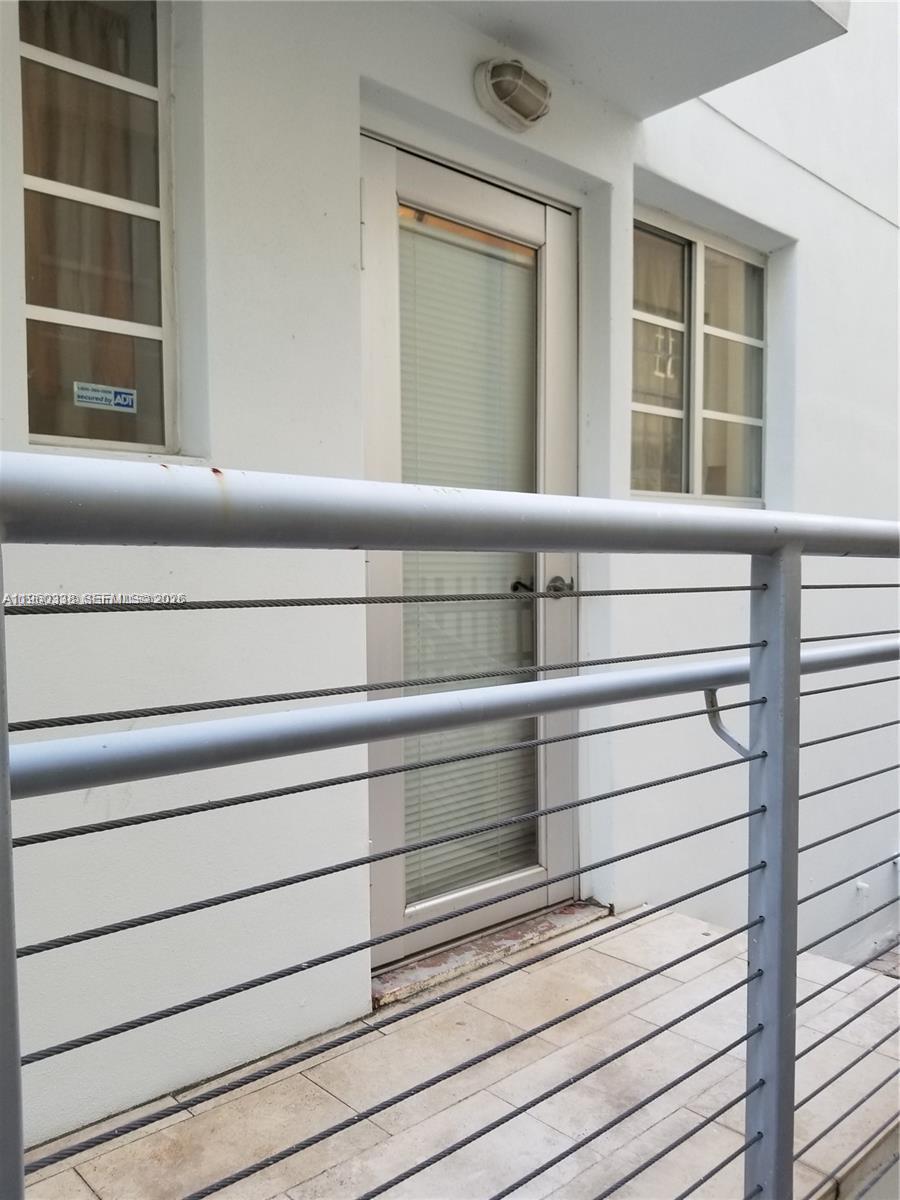 A white exterior wall features a glass door, two windows, and a metal cable railing — 1045 Meridian Ave # 5, Miami Beach FL 33139, MIAMI BEACH, FL