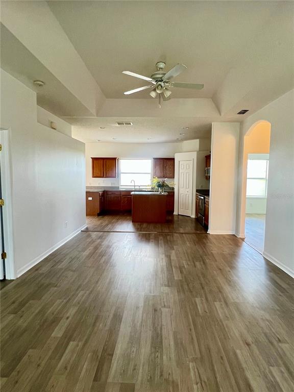 An open-concept kitchen with wood cabinets and a central island overlooks a spacious living area — 2234 N NORMANDY BOULEVARD, DELTONA, FL