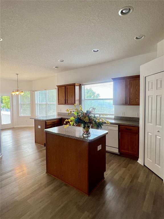 A kitchen features wood cabinets, a granite-topped island, and light wood-look flooring — 2234 N NORMANDY BOULEVARD, DELTONA, FL