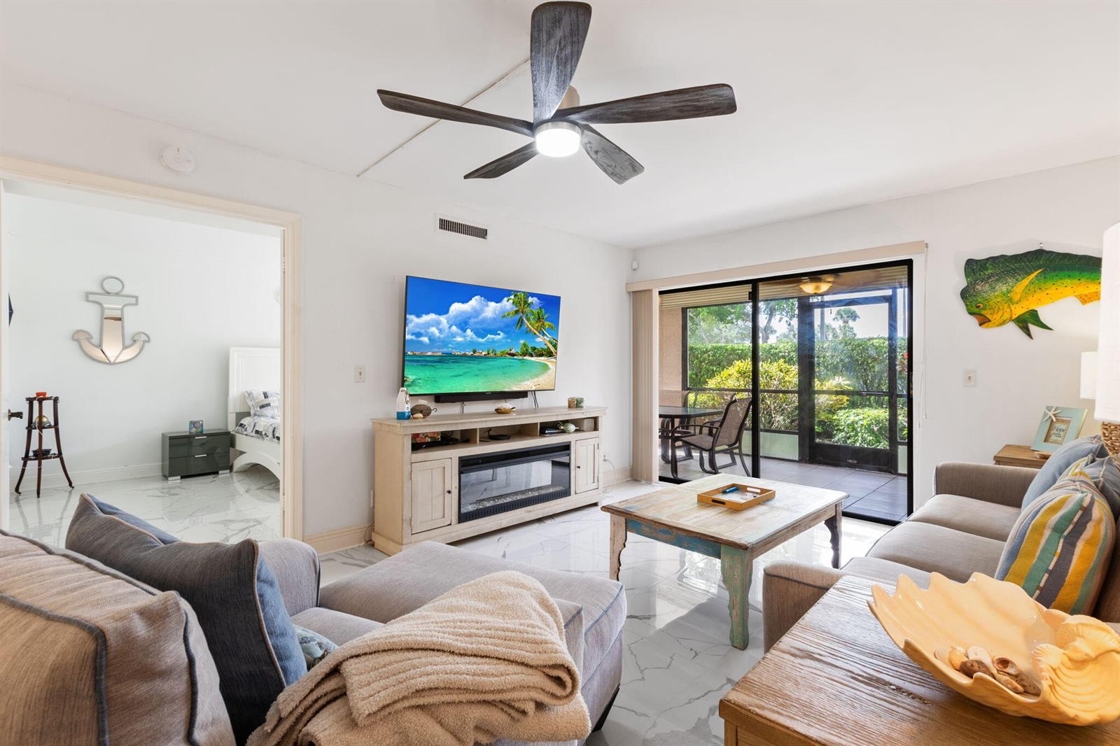 A living room features a ceiling fan, fireplace console, tile floors, and a screened patio — 10110 Cedar Point Boulevard # 102, Boynton Beach FL 33437, BOYNTON BEACH, FL