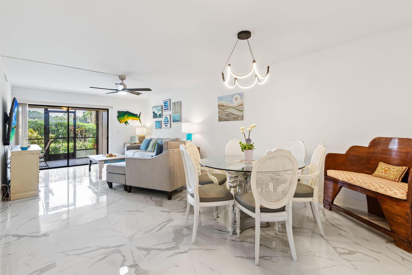 A bright living and dining area features white marble floors, a glass table, and patio access — 10110 Cedar Point Boulevard # 102, Boynton Beach FL 33437, BOYNTON BEACH, FL