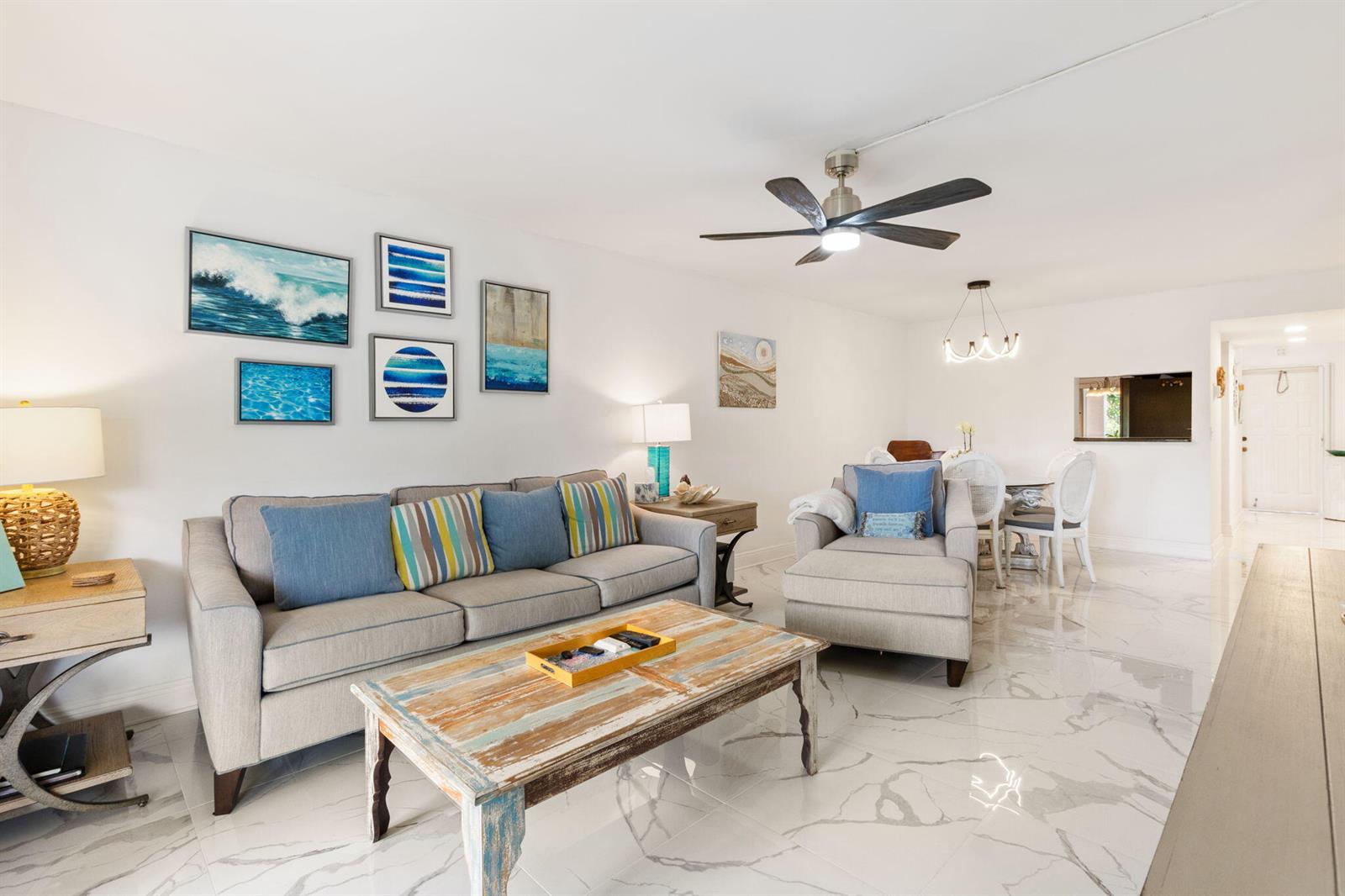 A living room with a grey sofa, coffee table, and white marble-look tile flooring — 10110 Cedar Point Boulevard # 102, Boynton Beach FL 33437, BOYNTON BEACH, FL
