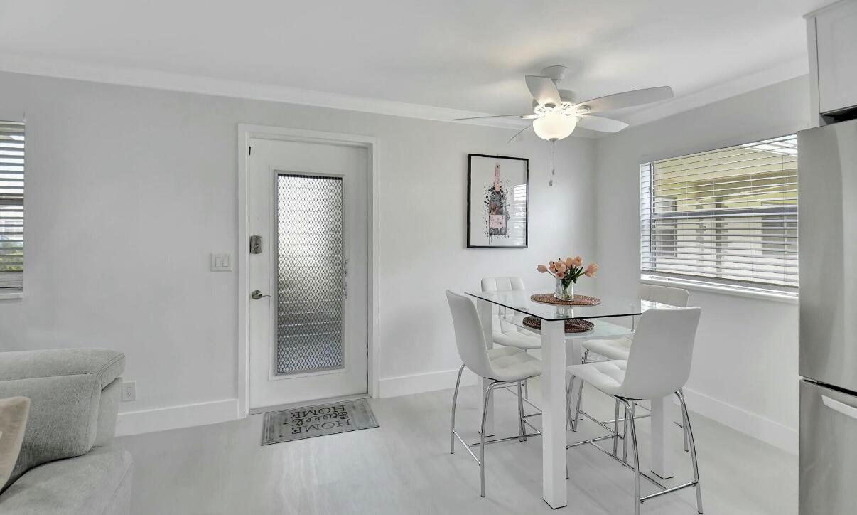 A dining area features a glass-topped table, four white chairs, and a white front door — 581 Monaco Boulevard # 581, Delray Beach FL 33446, DELRAY BEACH, FL