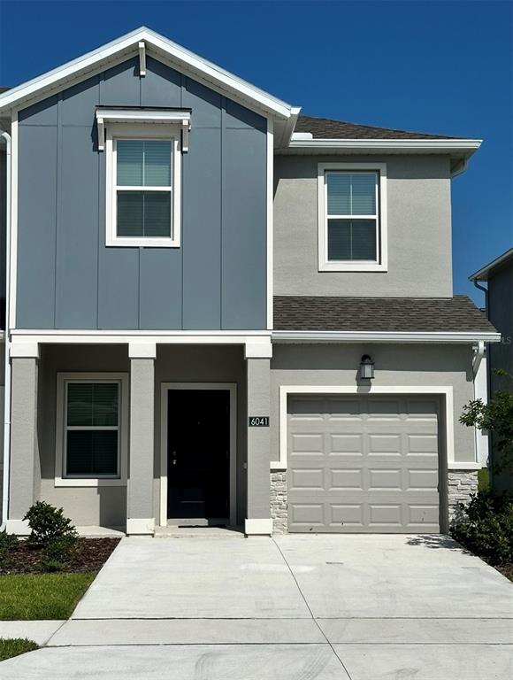 A two-story house features blue vertical siding, gray stucco, a garage, and a concrete driveway — 6041 ZEN WAY, CLERMONT, FL