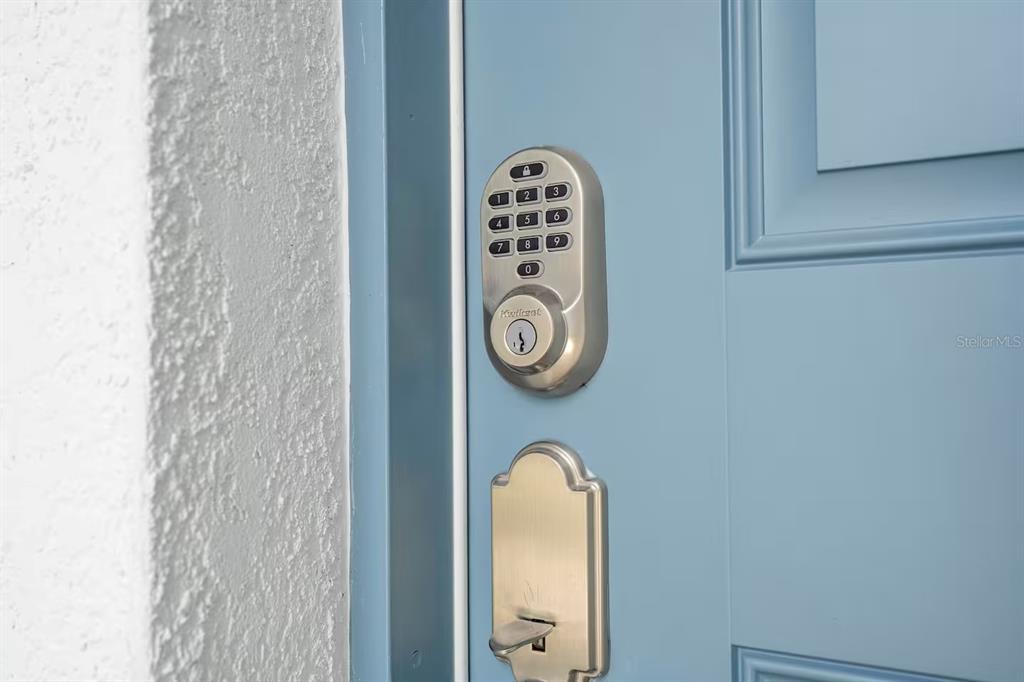 A blue door features a Kwikset electronic keypad deadbolt and a matching handle set — 10437 EBB TIDE LANE, ORLANDO, FL