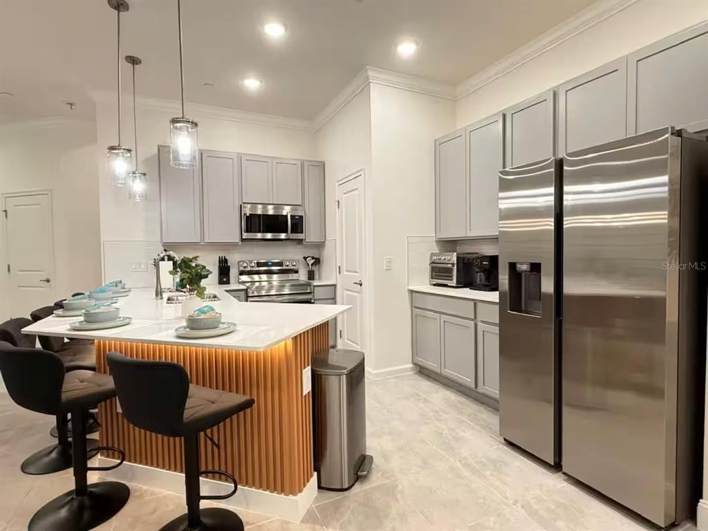 A modern kitchen features gray cabinets, stainless steel appliances, and a slatted wood kitchen island — 10437 EBB TIDE LANE, ORLANDO, FL