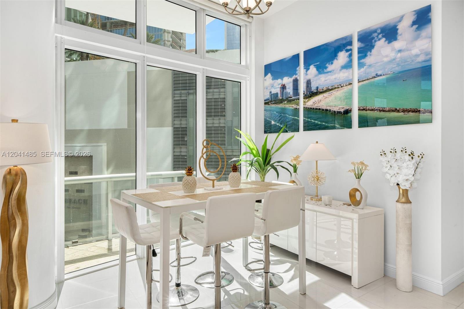 A bright dining area features a white table, modern bar stools, and coastal wall art — 480 NE 30th St # 501, Miami FL 33137, MIAMI, FL