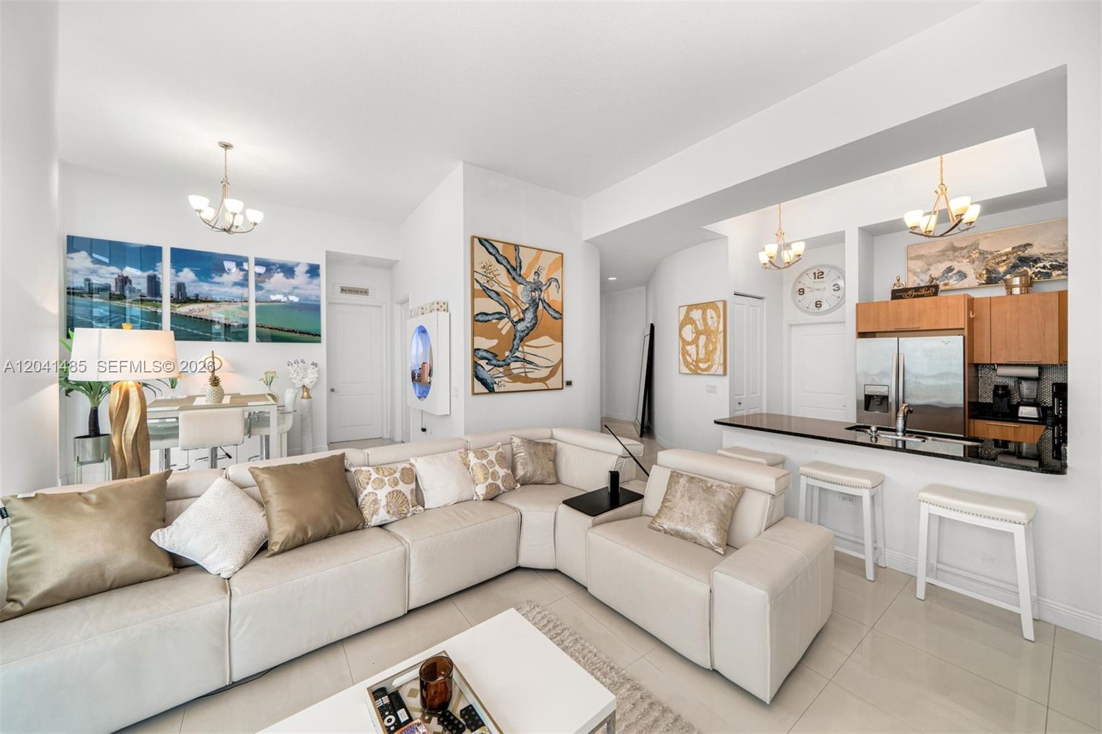 A living room with a large sectional sofa, open kitchen, and neutral tile flooring — 480 NE 30th St # 501, Miami FL 33137, MIAMI, FL