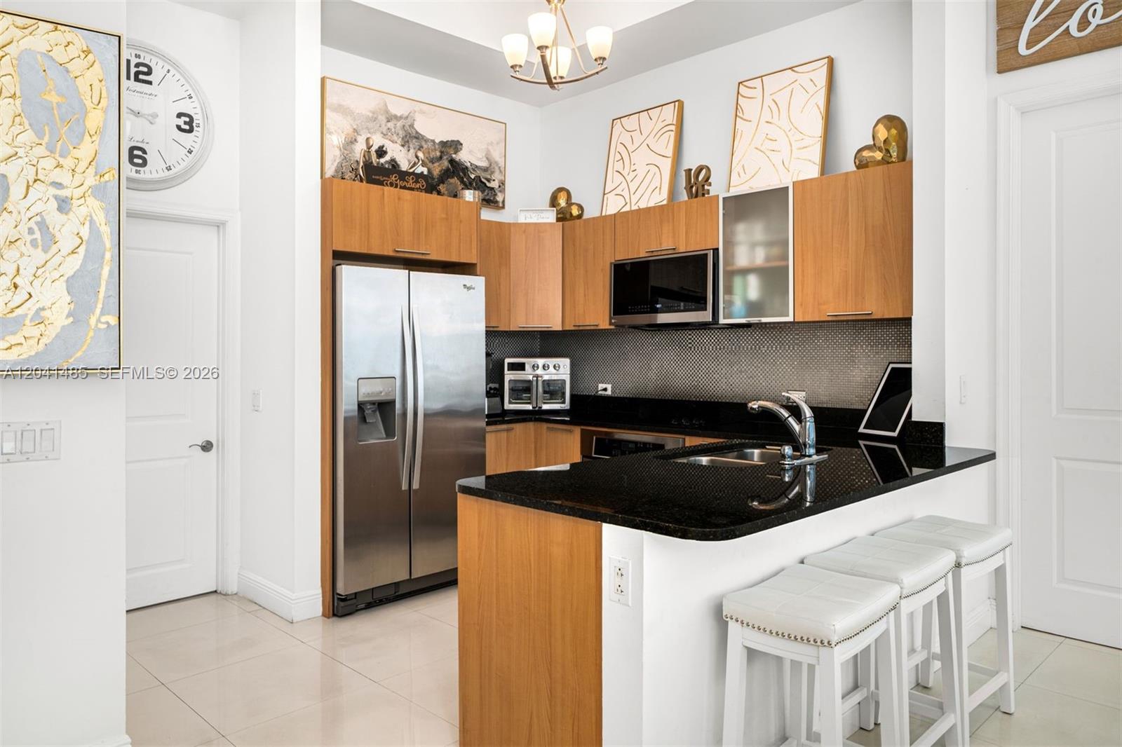 A kitchen features wood cabinets, black granite countertops, stainless steel appliances, and white bar stools — 480 NE 30th St # 501, Miami FL 33137, MIAMI, FL