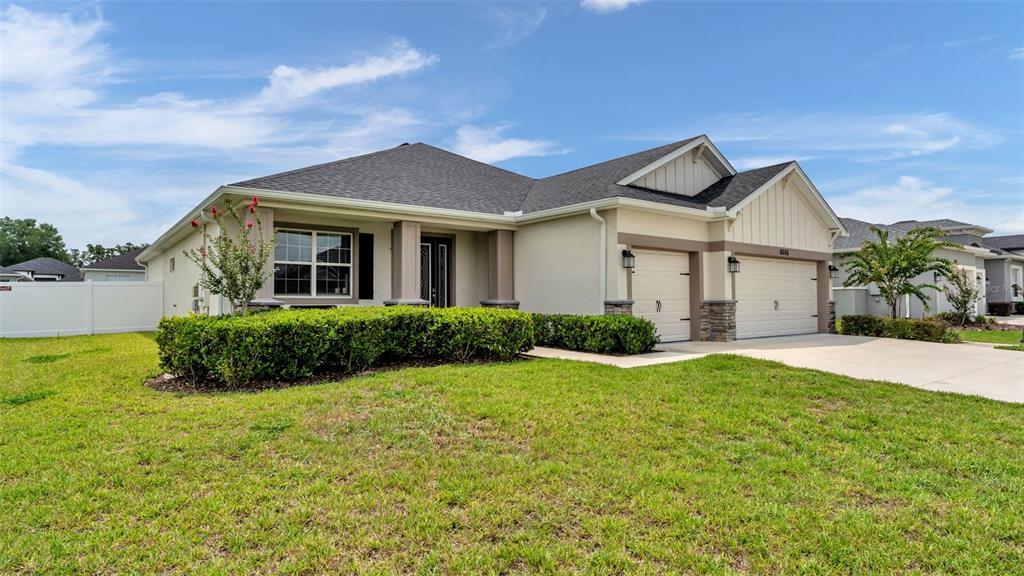 A single-story house with a beige stucco exterior, stone accents, and a two-car garage — 6686 TREYMONT DRIVE, LAKELAND, FL