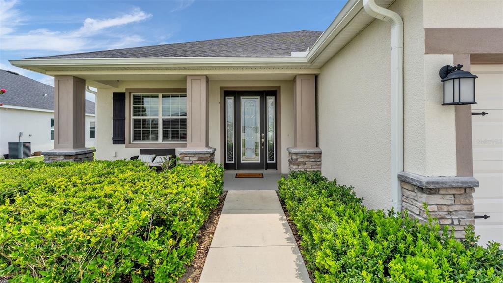 The front exterior of a house features a covered porch, stone pillars, and a walkway — 6686 TREYMONT DRIVE, LAKELAND, FL