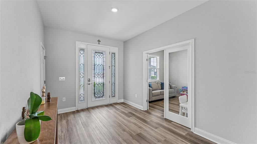 An entryway features wood-look flooring, a glass-paneled front door, and French doors leading to a room — 6686 TREYMONT DRIVE, LAKELAND, FL