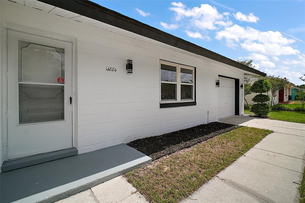 A white house exterior features a front door, a window, and an attached garage — 14884 SW 35TH CIRCLE, OCALA, FL