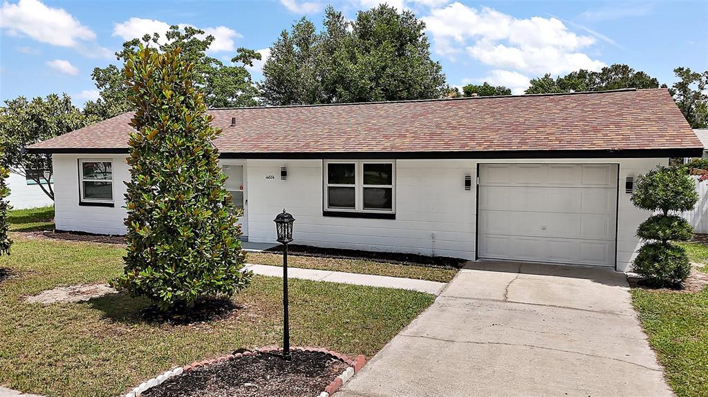 A single-story white house with a brown shingled roof, a garage, and a front lawn — 14884 SW 35TH CIRCLE, OCALA, FL