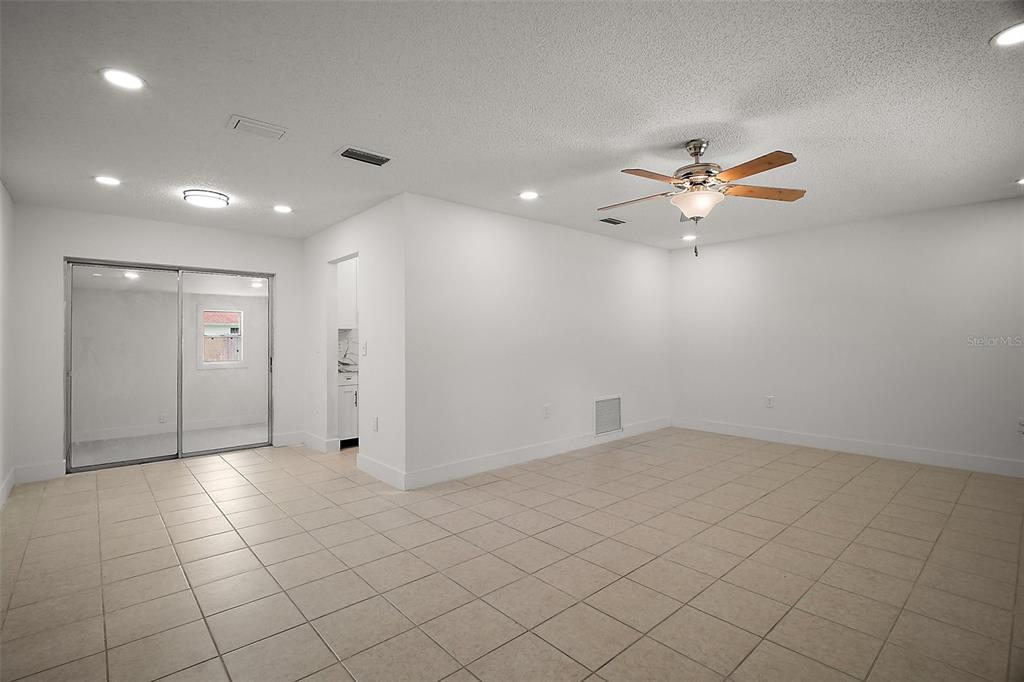 A spacious room with white walls, tile flooring, a ceiling fan, and sliding glass doors — 14884 SW 35TH CIRCLE, OCALA, FL