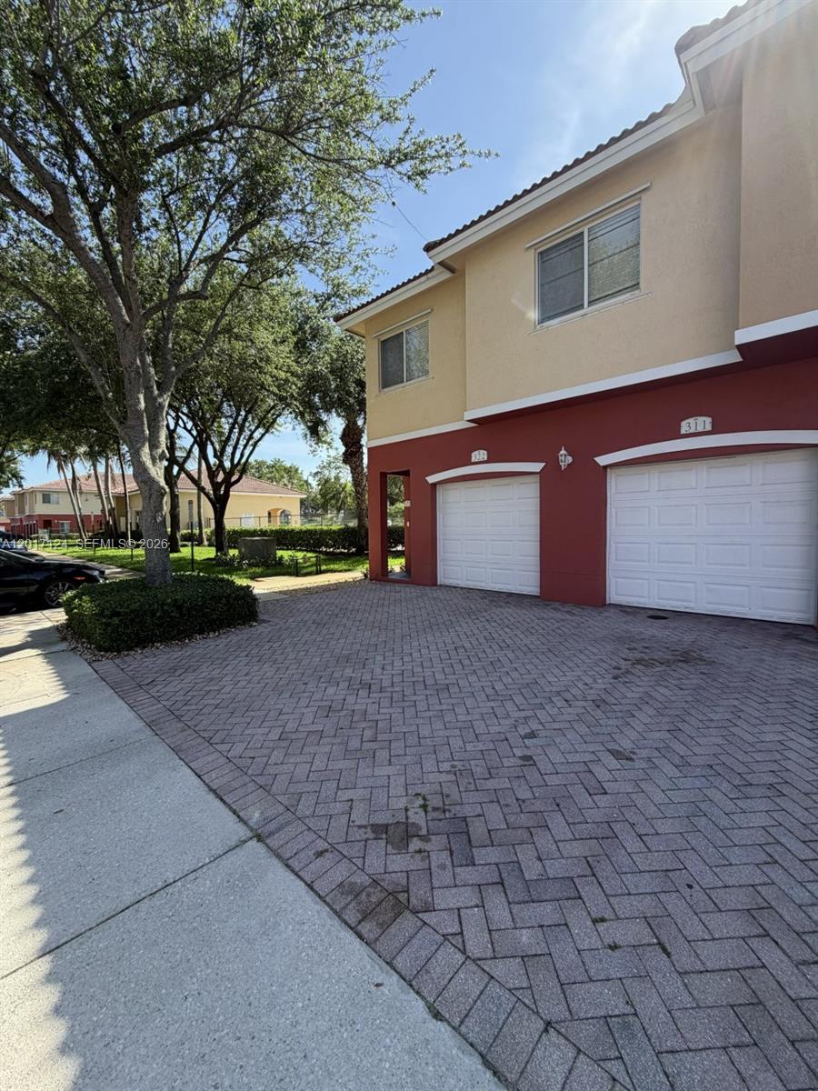 A two-story townhouse exterior features a brick-paved driveway and two white garage doors — 3335 Palomino Dr # 3, Davie FL 33024, DAVIE, FL