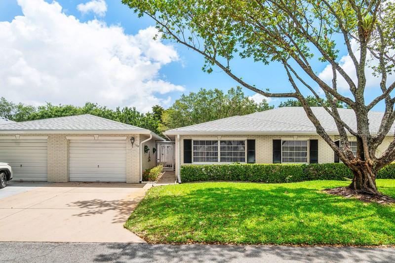 A single-story brick house with a two-car garage and a large tree in front — 10116 S 44TH AVENUE S UNIT 328, BOYNTON BEACH, FL
