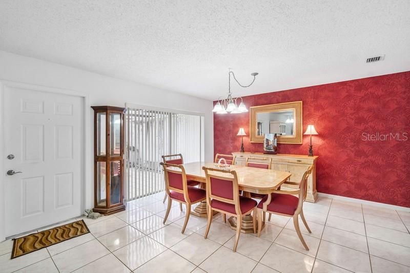 A dining room features a red patterned accent wall, tile flooring, and a wooden table — 10116 S 44TH AVENUE S UNIT 328, BOYNTON BEACH, FL