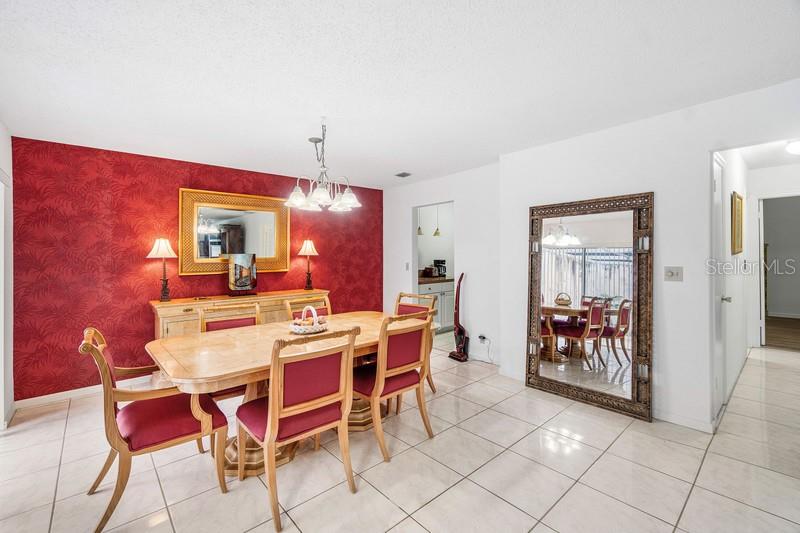 A dining room features a red accent wall, a wooden table, and a large floor mirror — 10116 S 44TH AVENUE S UNIT 328, BOYNTON BEACH, FL