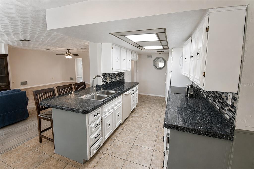A kitchen with white cabinets, dark patterned countertops, and a tiled floor — 22128 BRONXVILLE AVENUE, PORT CHARLOTTE, FL