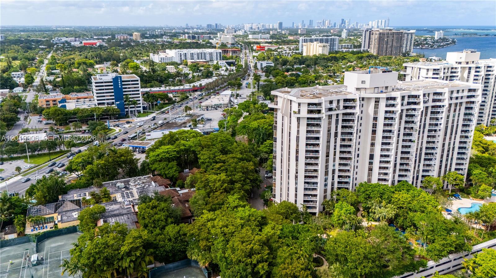An aerial view shows a tall residential building surrounded by trees, roads, and other structures — 2000 Towerside Ter # 311, Miami FL 33138, MIAMI, FL