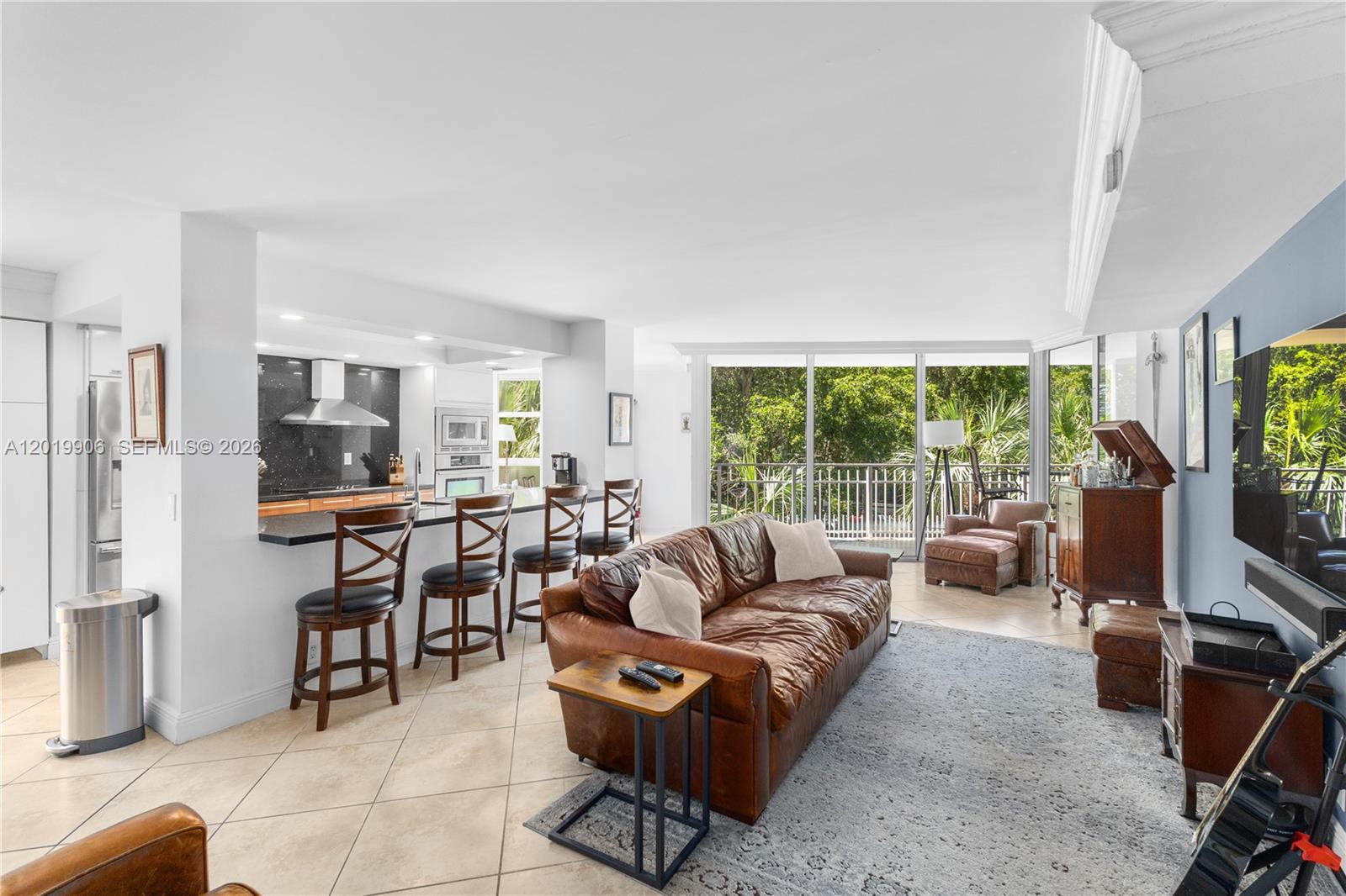 A living room with a brown leather sofa, breakfast bar, and floor-to-ceiling windows — 2000 Towerside Ter # 311, Miami FL 33138, MIAMI, FL