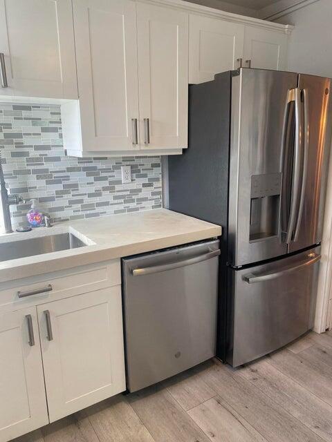 A kitchen features white cabinets, stainless steel appliances, and a gray-toned tile backsplash — 3215 S Ocean Boulevard # 402, Highland Beach FL 33487, HIGHLAND BEACH, FL