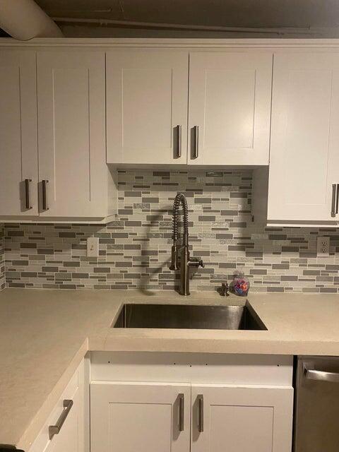 A kitchen sink area features white cabinets, a light countertop, and a gray-toned mosaic backsplash — 3215 S Ocean Boulevard # 402, Highland Beach FL 33487, HIGHLAND BEACH, FL