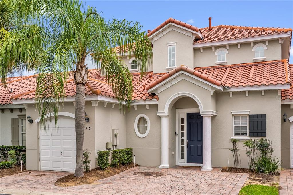 A two-story house with a tile roof, a palm tree, and a paved driveway — 516 BRUNELLO DRIVE, DAVENPORT, FL