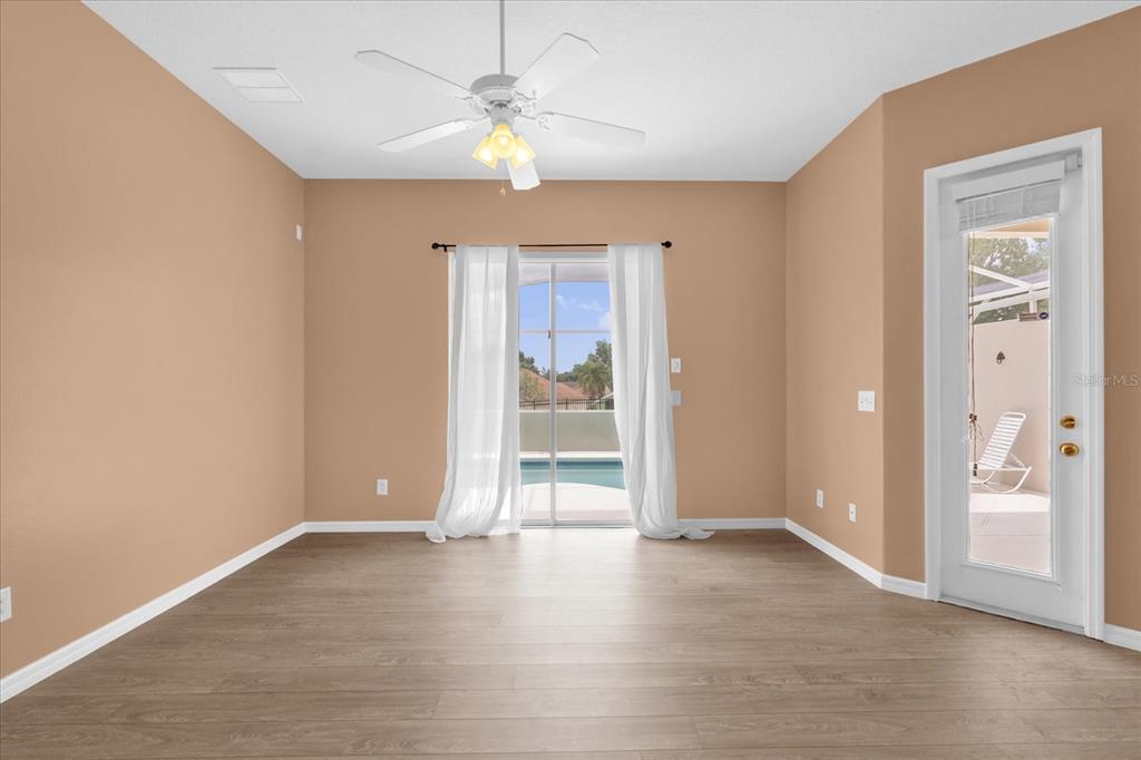 An empty room with light wood flooring, tan walls, a ceiling fan, and sliding glass doors — 516 BRUNELLO DRIVE, DAVENPORT, FL