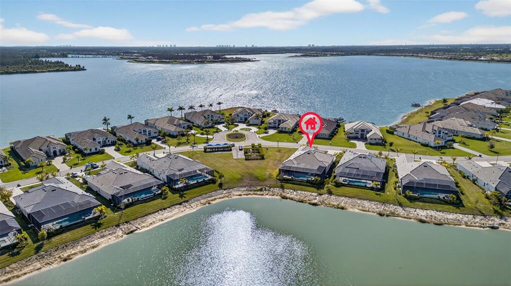 An aerial view shows a residential neighborhood with houses situated along a large lake — 17395 BLUE SAPPHIRE DRIVE, FORT MYERS, FL