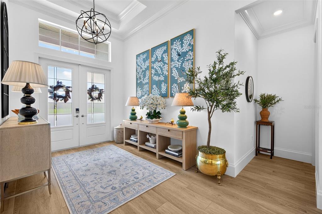 A bright entryway features a light wood console table, a patterned rug, and double doors — 17395 BLUE SAPPHIRE DRIVE, FORT MYERS, FL