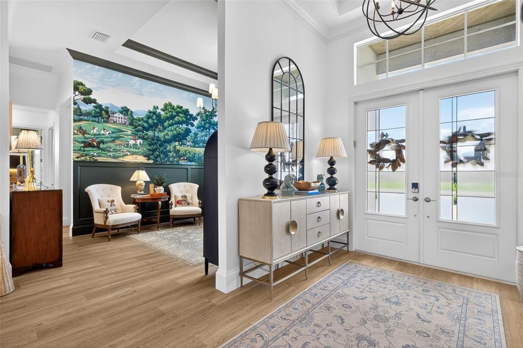A bright foyer features a mural wall, wood-look flooring, and a double-door entryway — 17395 BLUE SAPPHIRE DRIVE, FORT MYERS, FL
