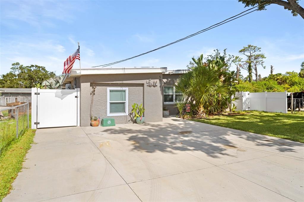 A single-story house with a concrete driveway, white gate, and American flag — 5041 MAPLEWOOD, HERNANDO BEACH, FL