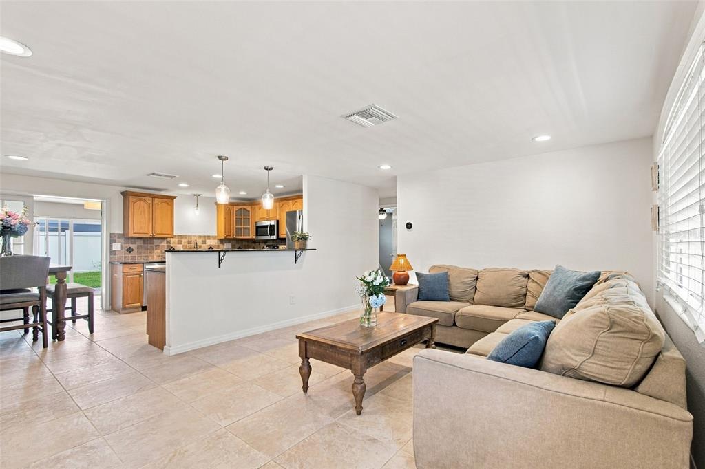 A living room with tile floors and a sectional sofa opens to a kitchen area — 8467 77TH AVENUE, SEMINOLE, FL