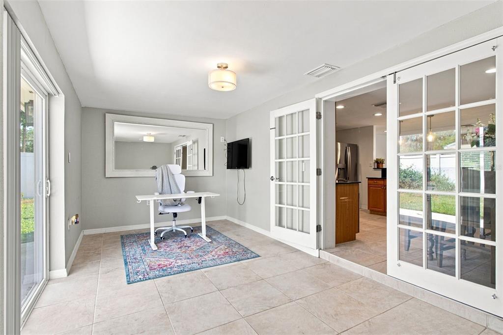 A home office with tile floors, a desk, a large mirror, and glass-paned double doors — 8467 77TH AVENUE, SEMINOLE, FL