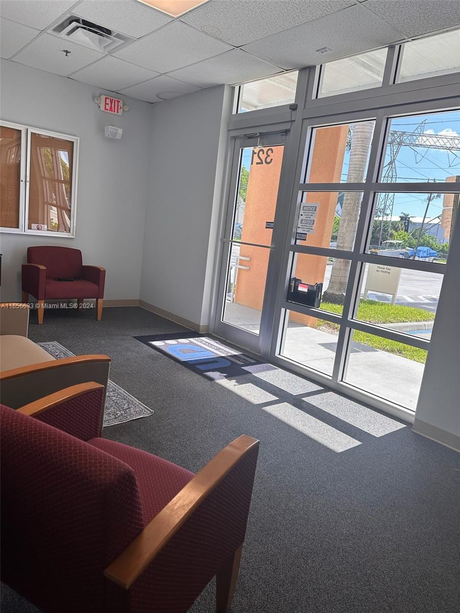 A waiting area features maroon armchairs, gray carpeting, and a glass door leading outside — FORT LAUDERDALE, FL