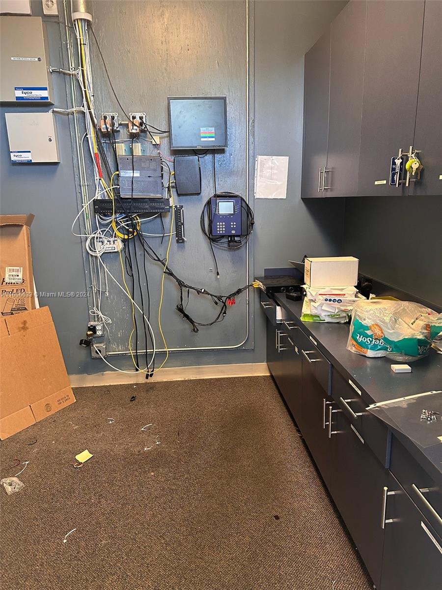 A utility or server room features wall-mounted electronics, exposed wiring, and dark cabinetry — FORT LAUDERDALE, FL